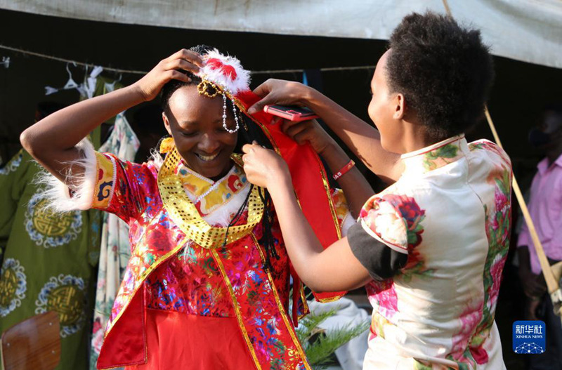 Mmoja wa wanafunzi (Kushoto) akijaribu vazi la asili la China wakati wa Maonesho ya Utamaduni wa China katika Chuo Kikuu cha Rwanda, Chuo Kishiriki cha Elimu cha Kampasi ya Rukara, Mashariki mwa Rwanda, Novemba 10, 2021. Vivutio vinavyoonesha utamaduni wa China vilijaza ukumbi wa wanafunzi katika chuo hicho. Kwa mara ya kwanza yakiandaliwa nje ya Mji Mkuu Kigali, tangu kuzuka kwa virusi vya korona, maonesho hayo kwa mwaka huu yalihusu kujionea utamaduni wa China kama sehemu ya sherehe za kuadhimisha miaka 50 ya kuanzishwa kwa uhusiano wa kidiplomasia kati ya China na Rwanda. (Xinhua/Ji Li)